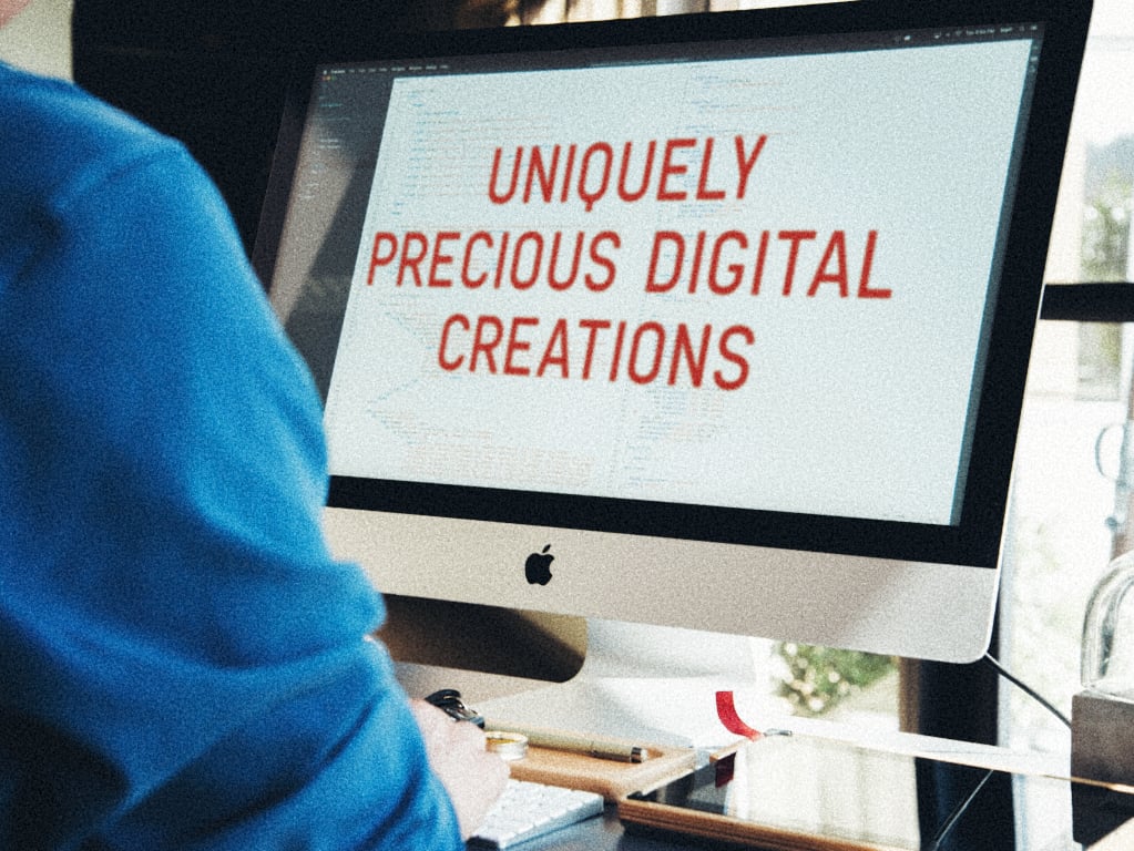 Man’s shoulder visible while working at large Mac screen displaying “uniquely precious digital creations”